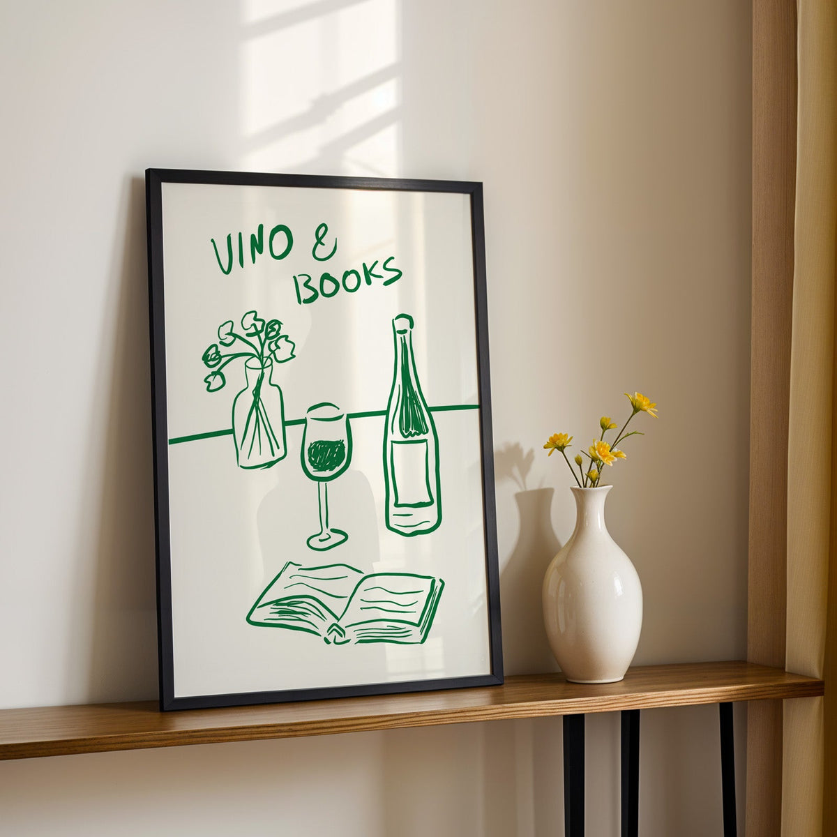Vino and books green line print in a black frame on a console table with daisies