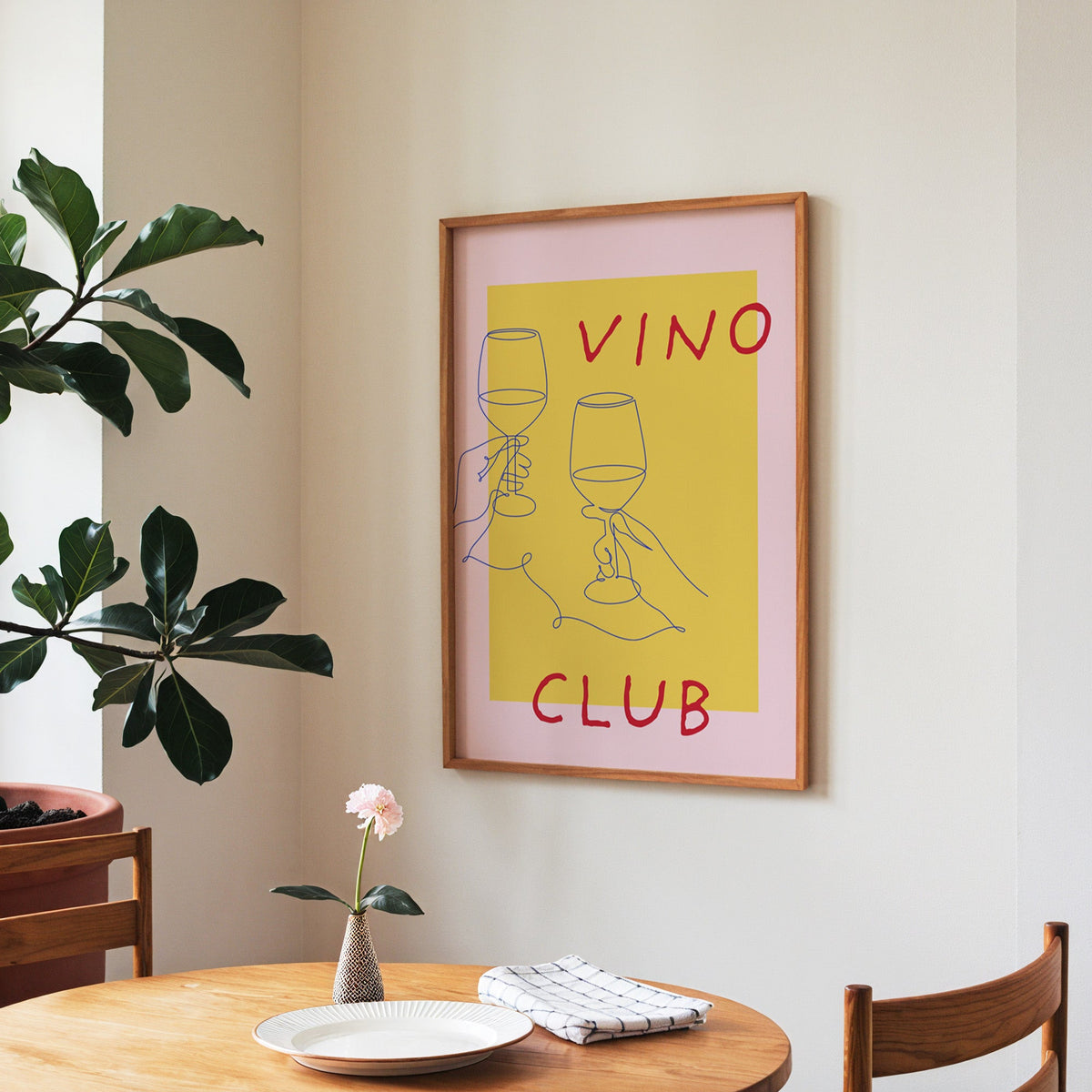 Vino Club print in a walnut frame above a round table beside a fiddle-leaf fig