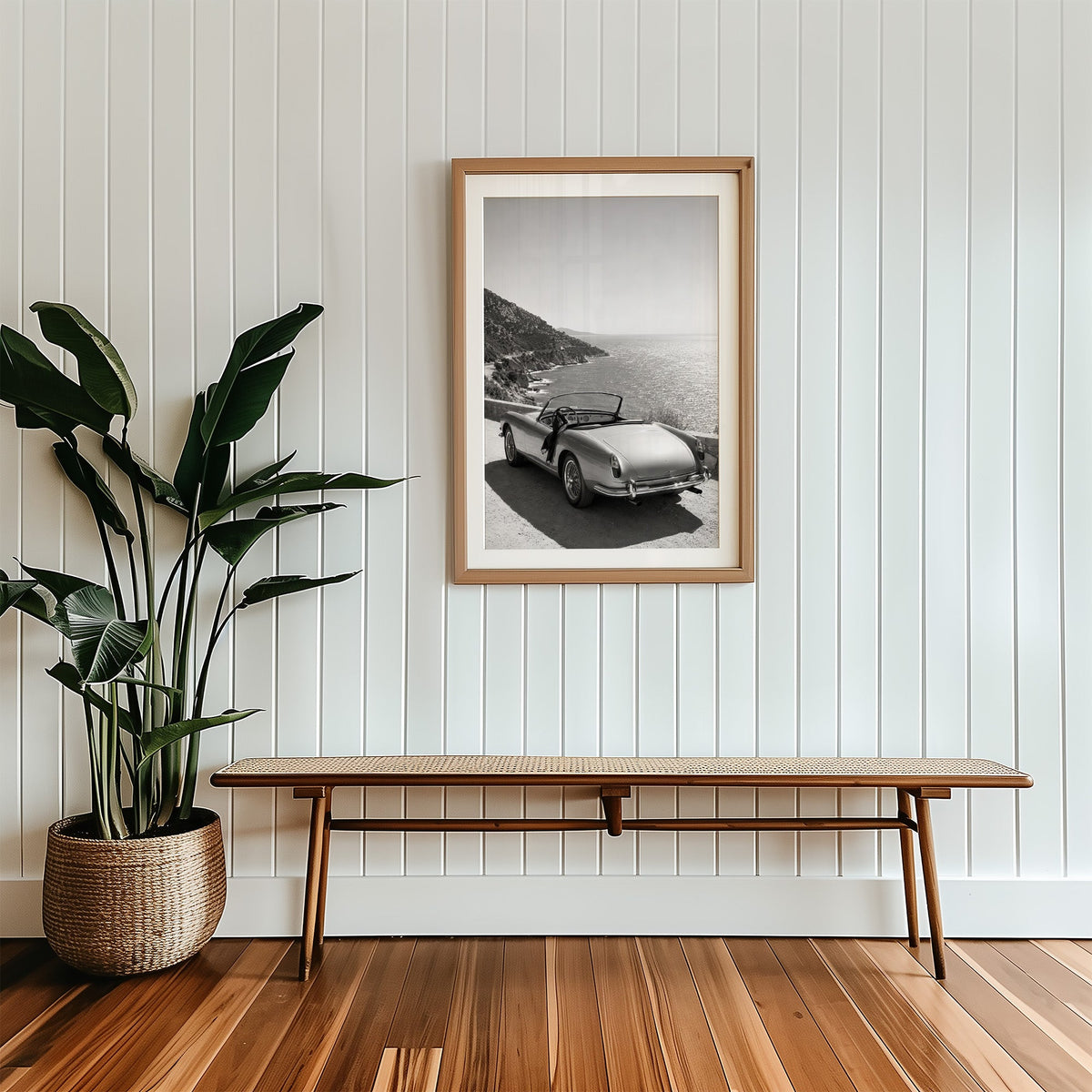 Vintage convertible parked above the sea print in a wood frame with a white mat above a cane bench