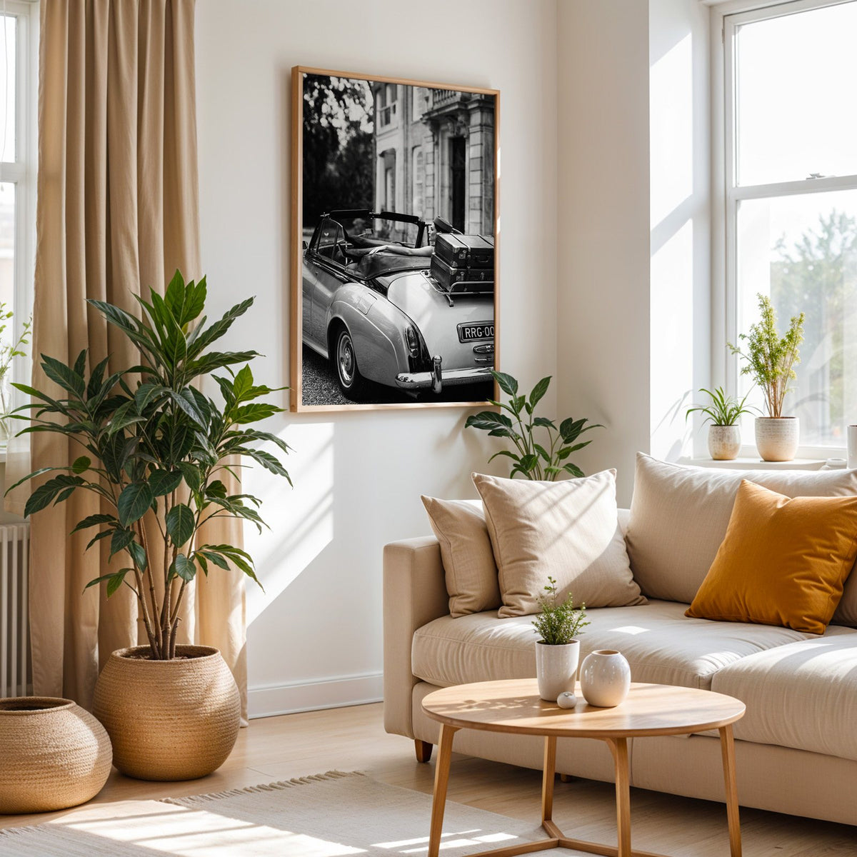 Woman in vintage convertible with leather suitcases print in an oak frame above a cream sofa beside woven planters