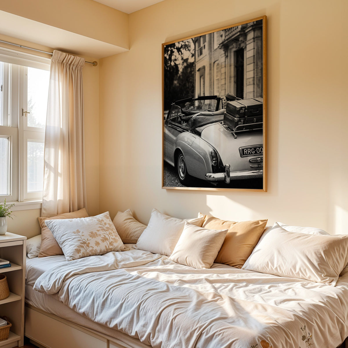 Woman in vintage convertible with leather suitcases print in an oak frame above a cream daybed in a sunny bedroom