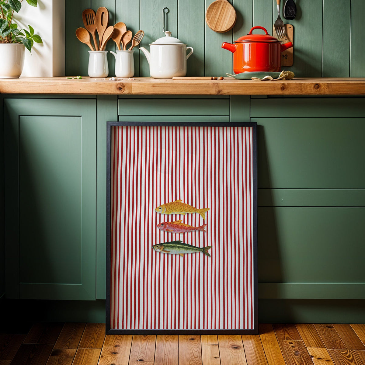 Vintage fish red stripe print in a black frame against sage green kitchen cabinets