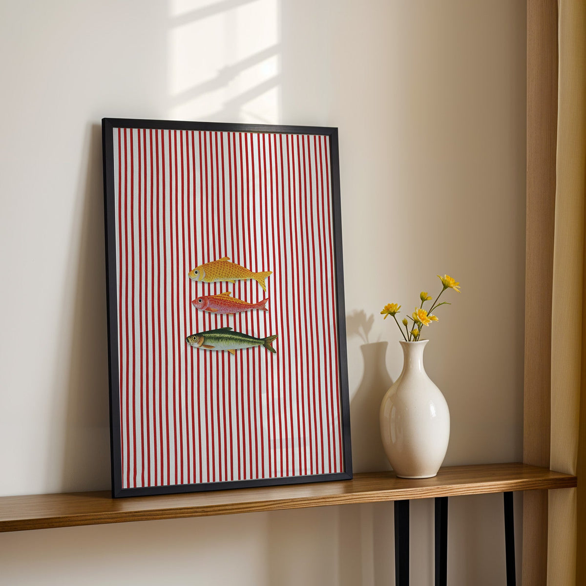 Vintage fish red stripe print in a black frame on a console table with daisies