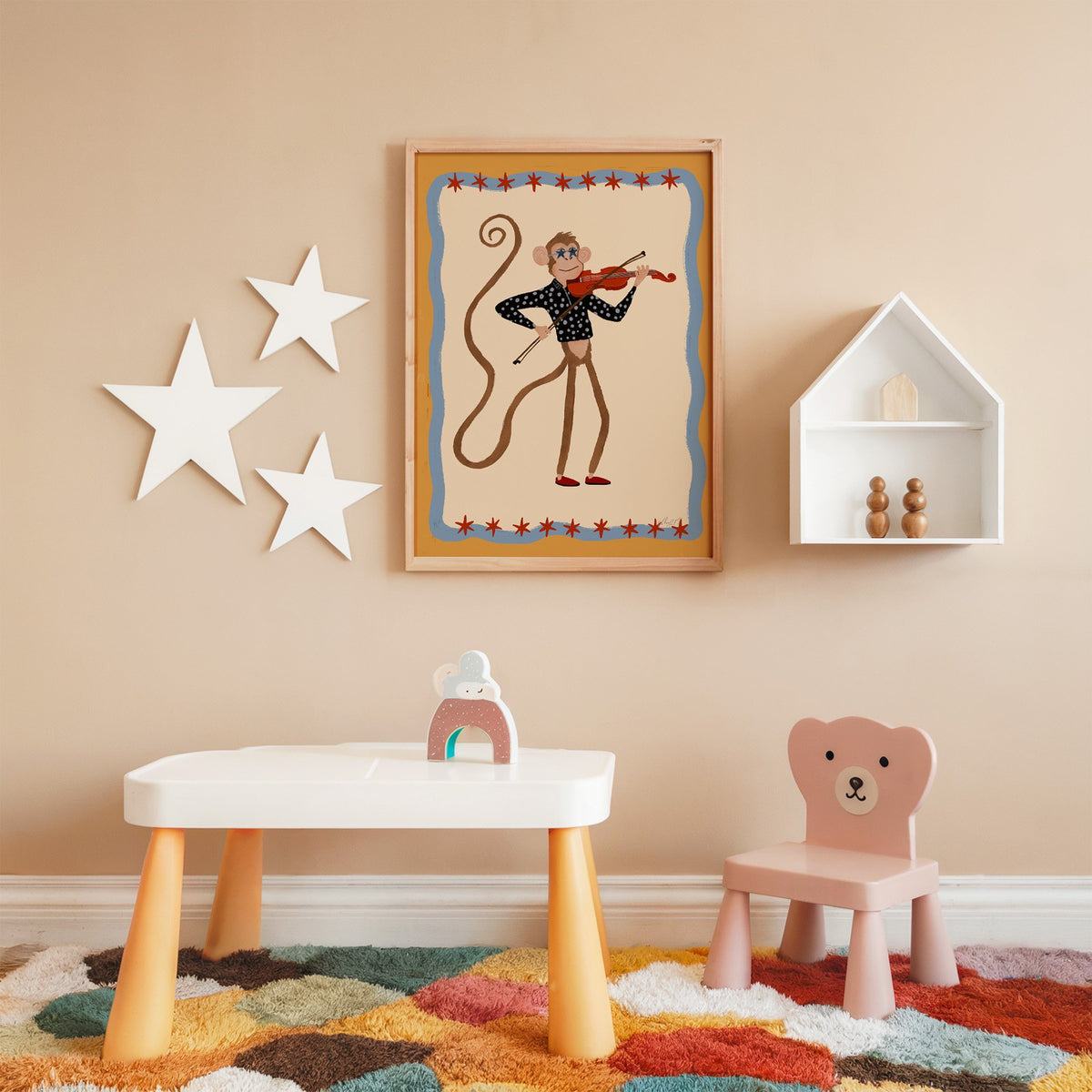Monkey playing red violin nursery print in an oak frame on a peach wall above a kids table with wall stars