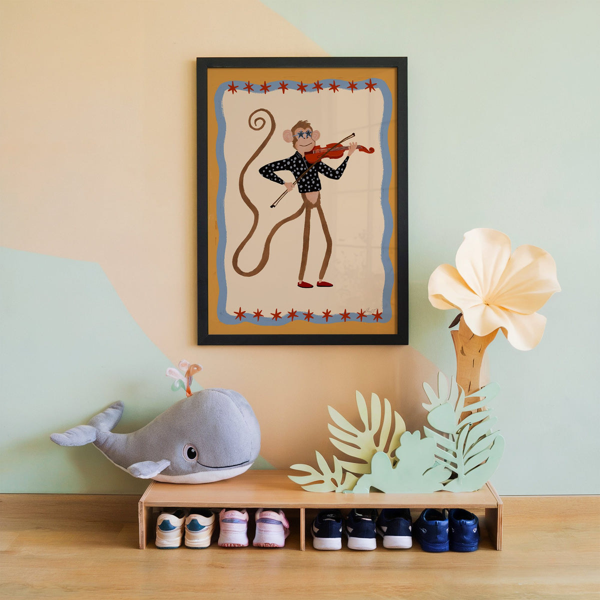 Monkey playing red violin nursery print in a black frame on a mint and peach wall above a whale plush