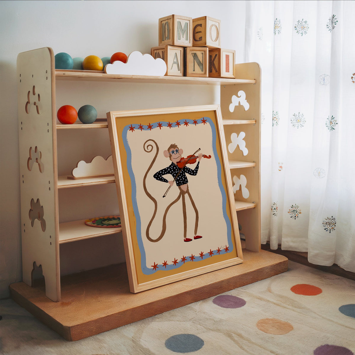 Monkey playing red violin nursery print in an oak frame leaning on a toy shelf with wooden letter blocks