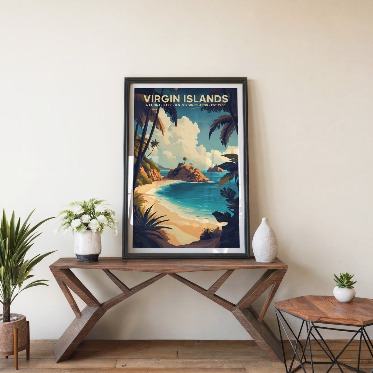 Virgin Islands poster in a black frame on an entryway console table beside white flowers and a yucca