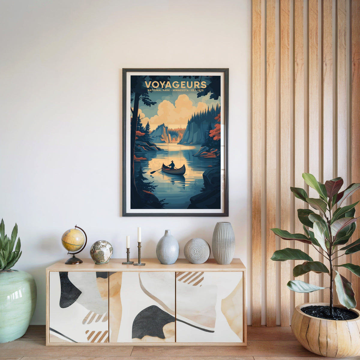 Voyageurs National Park print in a black frame above a light wood sideboard with a globe and ceramic vases