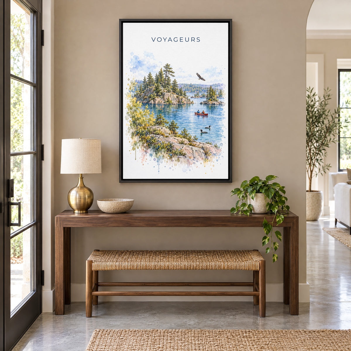 Voyageurs National Park watercolor print as a black floater canvas above a walnut console and woven bench in an entryway