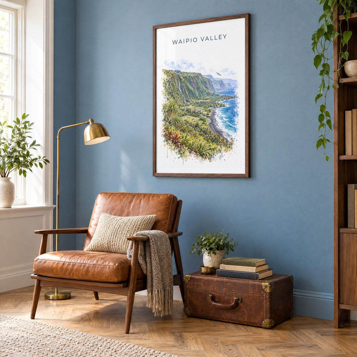 Waipio Valley watercolor print in a walnut frame on a blue wall above a leather armchair in a reading nook