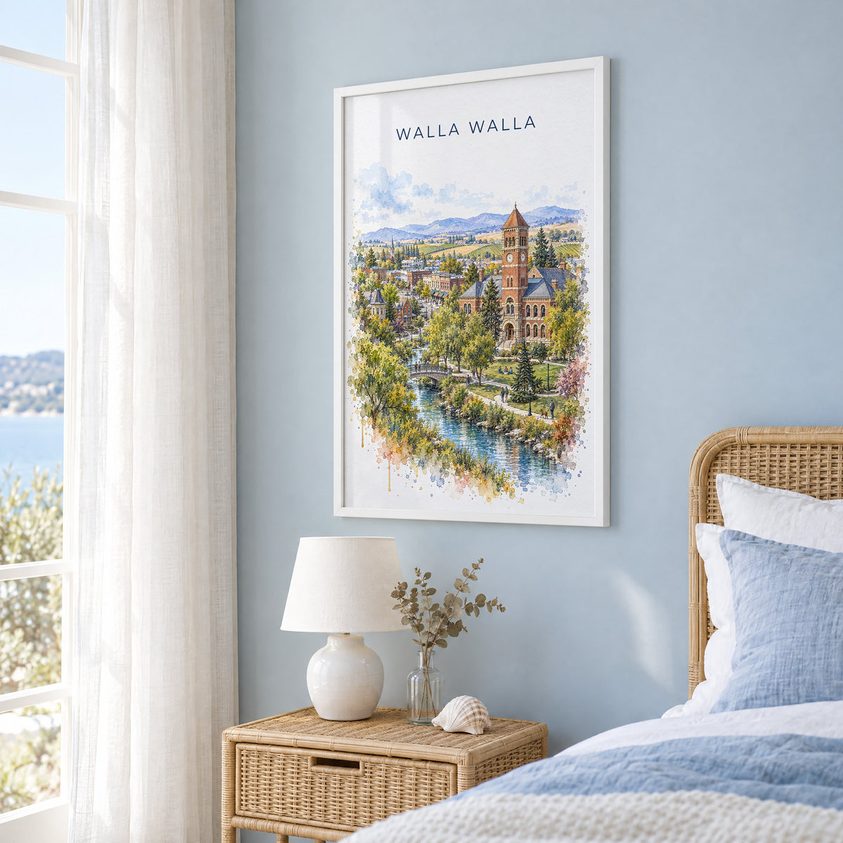 Walla Walla watercolor print in a white frame on a pale blue wall beside a rattan bed in a coastal bedroom