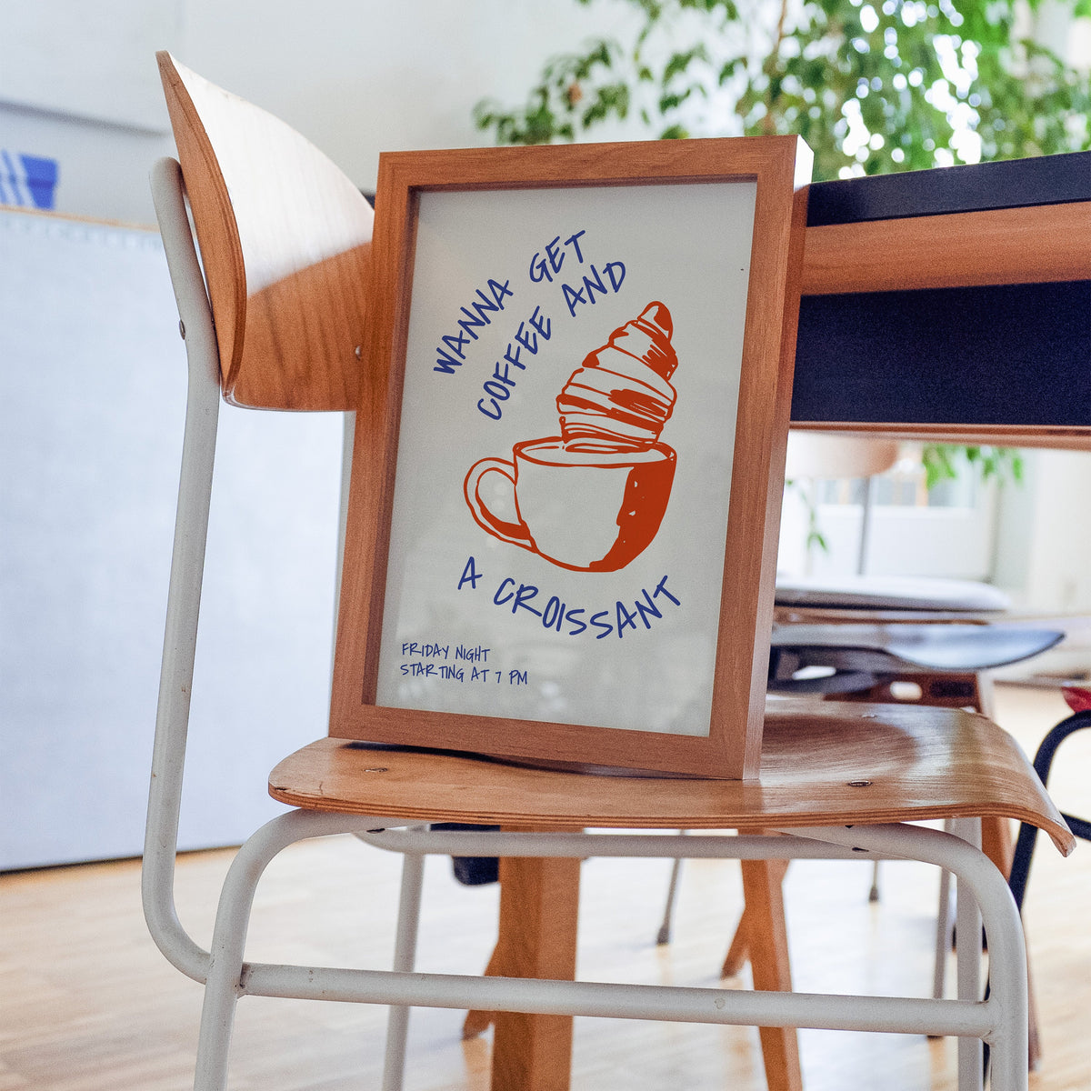 Wanna Get Coffee and a Croissant print in a walnut frame on a bentwood chair