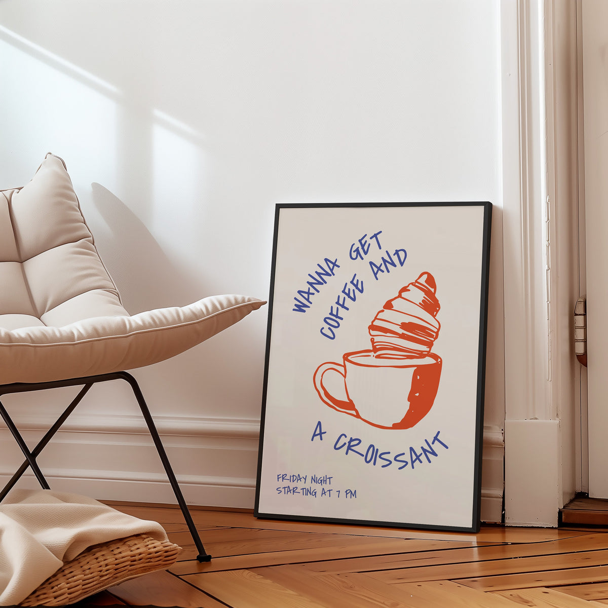 Wanna Get Coffee and a Croissant print in a black frame on a parquet floor