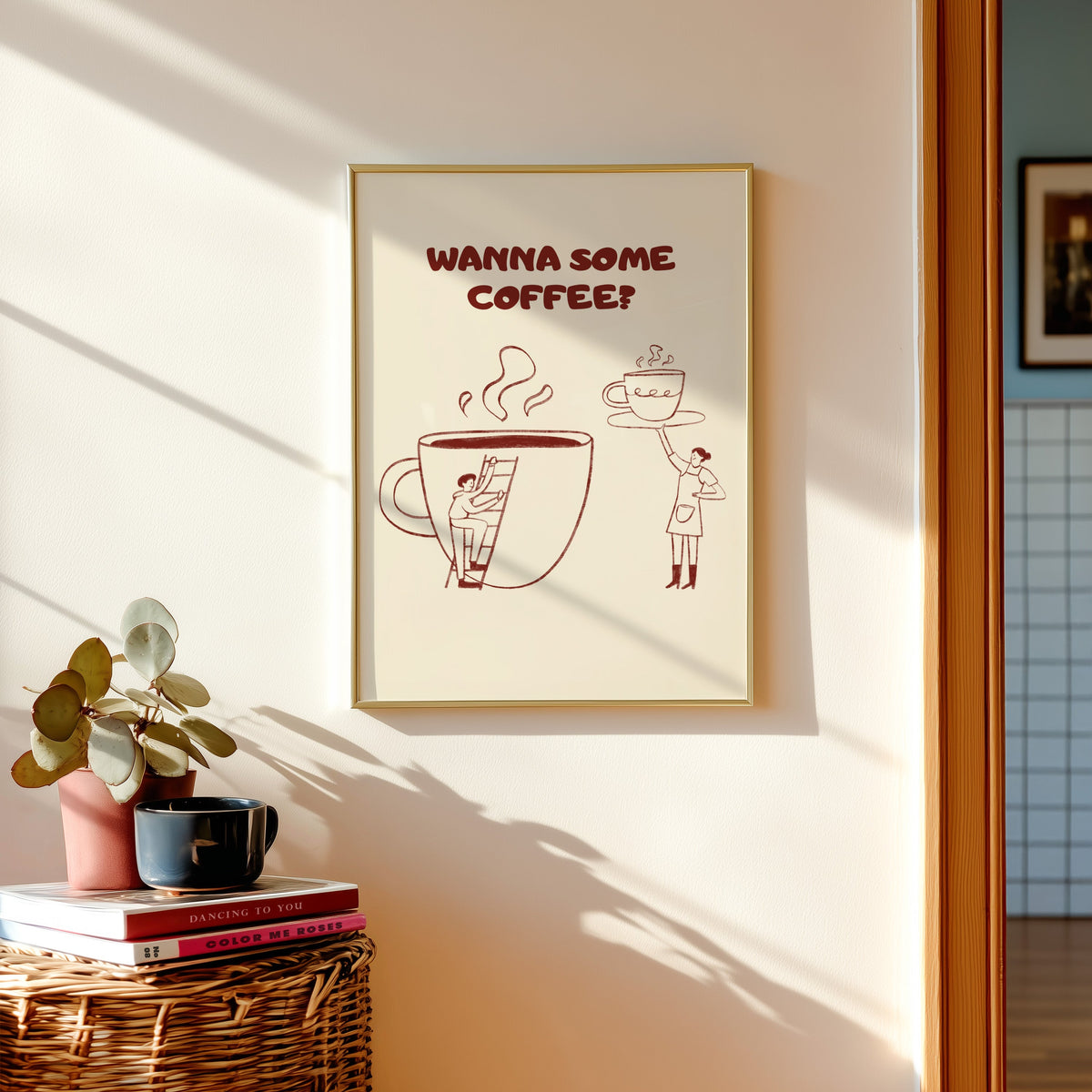Wanna Some Coffee print shown in a gold frame above a basket of books and a pilea plant