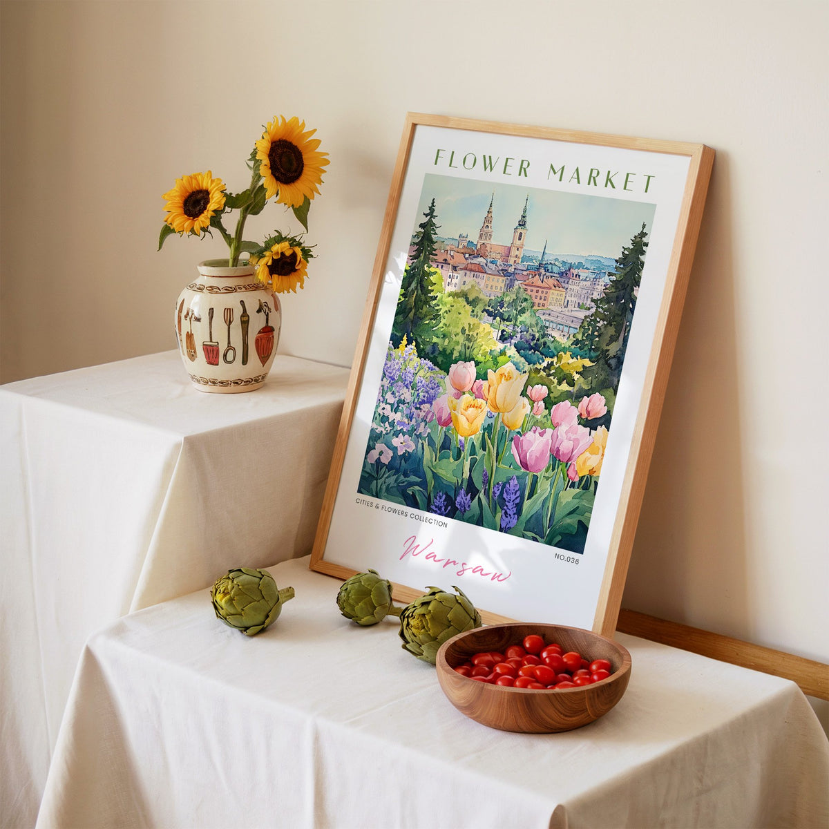 Warsaw flower market print in an oak frame leaning on a linen-draped table beside a vase of sunflowers
