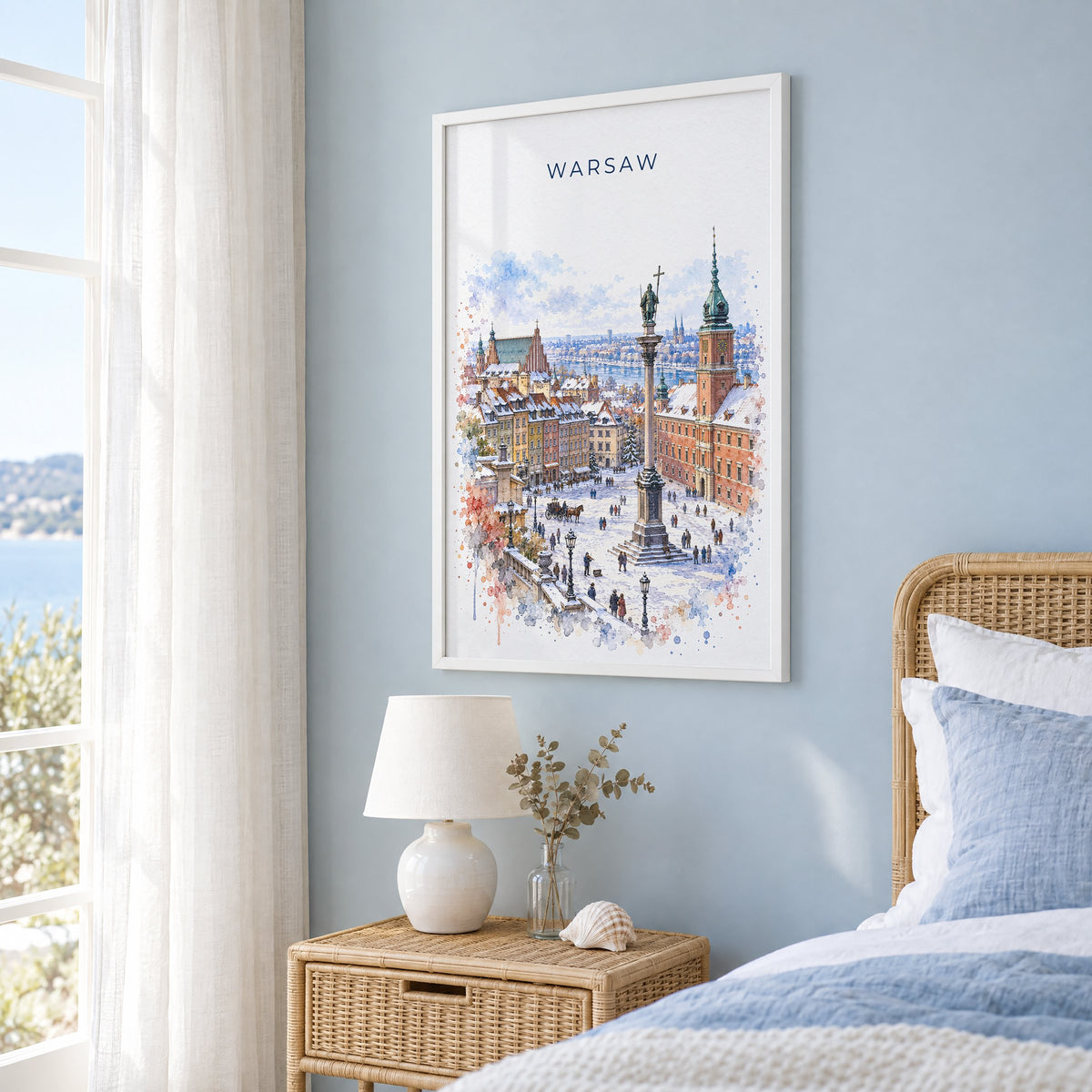 Warsaw watercolor print in a white frame on a pale blue wall beside a rattan bed in a coastal bedroom