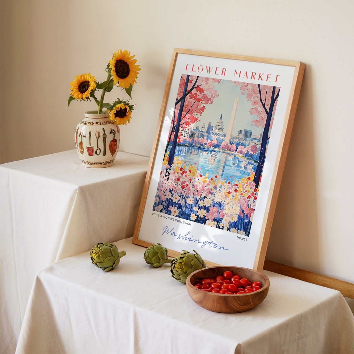 Washington DC flower market print in an oak frame leaning on a linen-draped table beside a vase of sunflowers