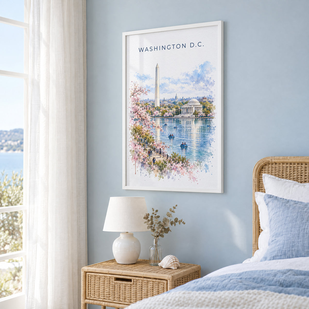 Washington, D.C. watercolor print in a white frame on a pale blue wall beside a rattan bed in a coastal bedroom