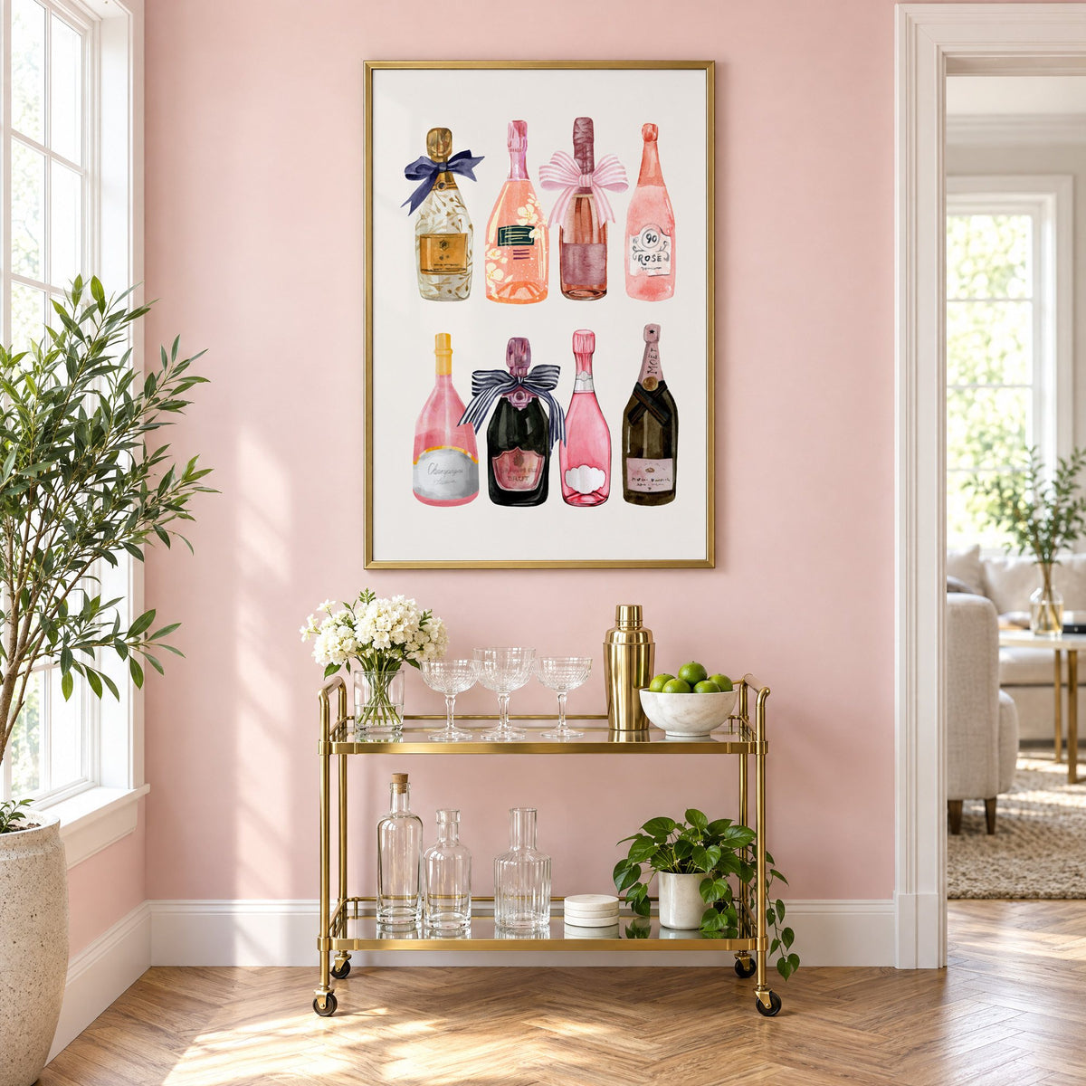 Watercolor champagne bottles print in a brass frame above a gold bar cart on a blush pink wall