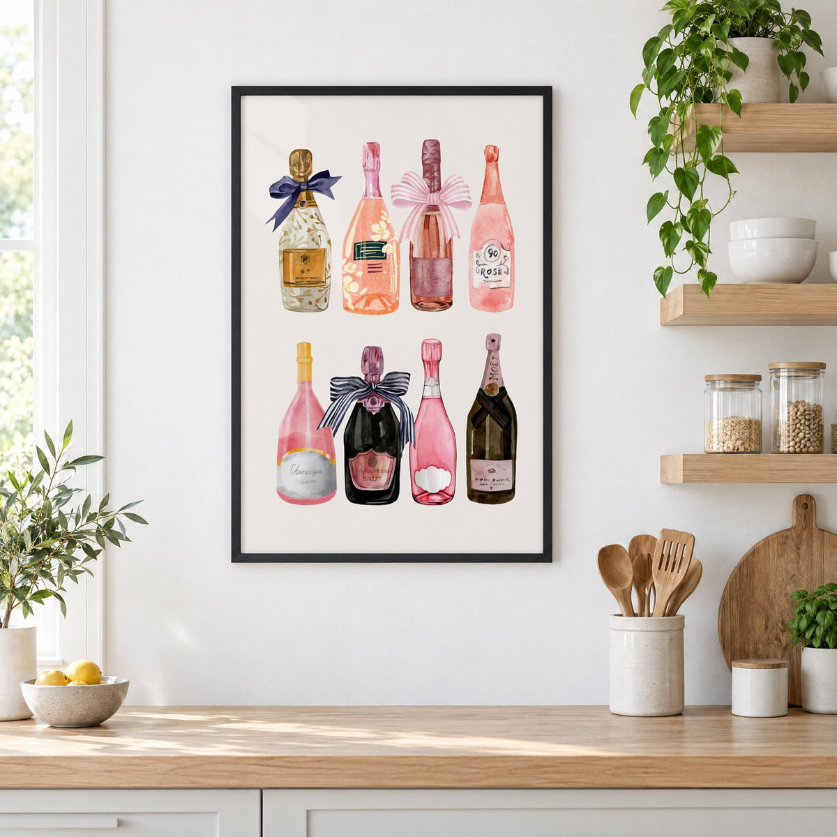 Watercolor champagne bottles print in a black frame in a white kitchen beside open wood shelves and glass jars
