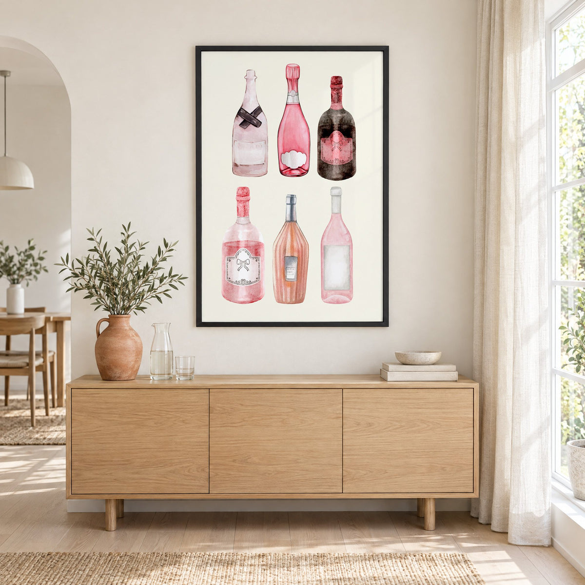 Six pink wine bottles watercolor print in a black frame above an oak sideboard with a terracotta vase of olive branches