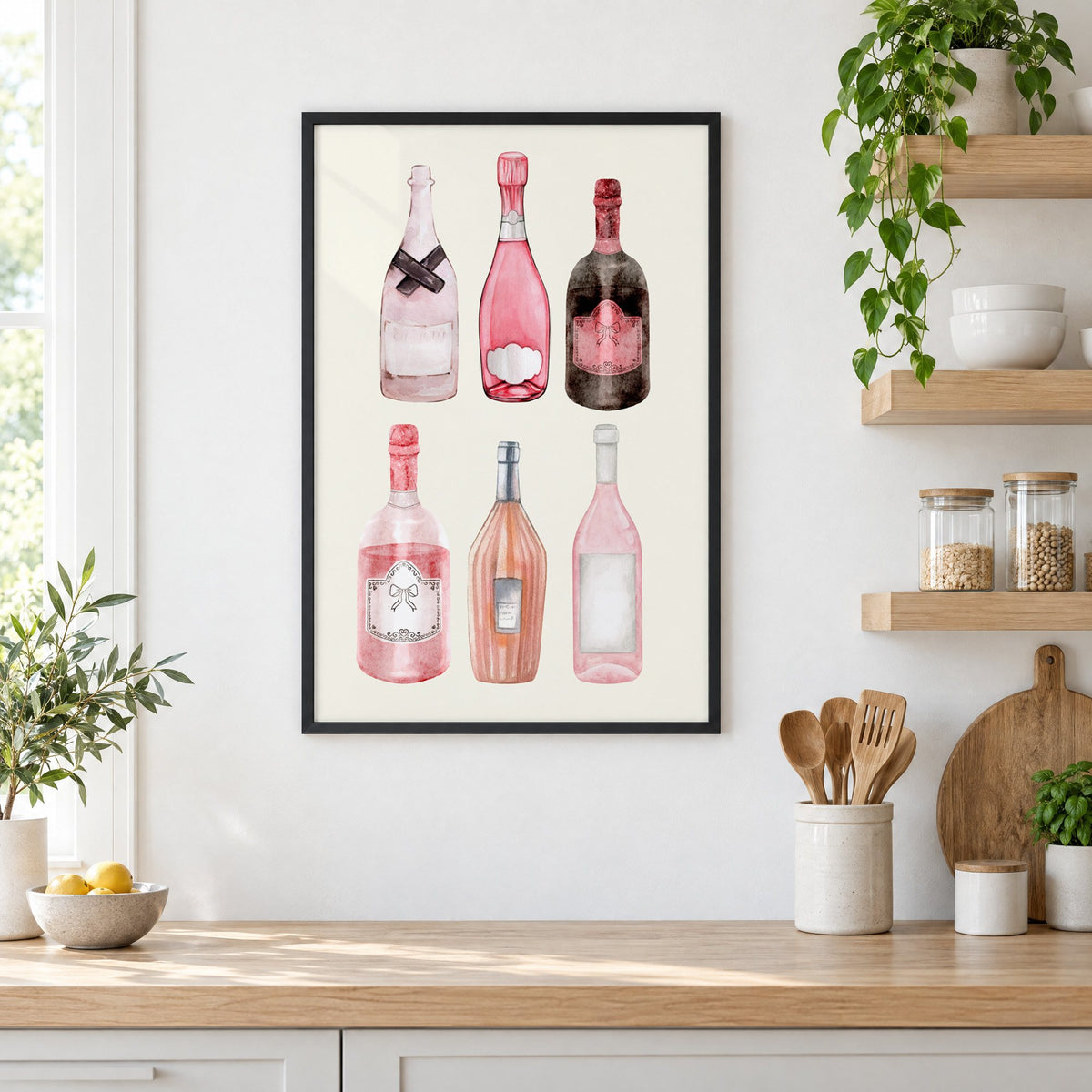 Six pink wine bottles watercolor print in a black frame in a white kitchen beside open wood shelves and glass jars