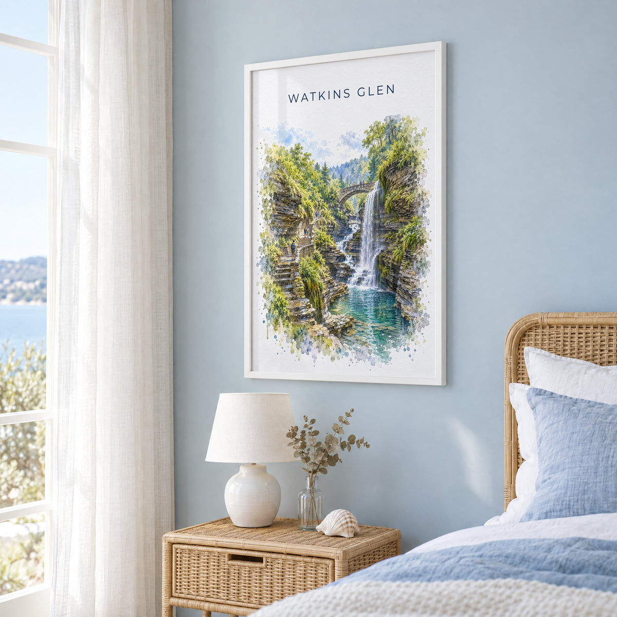 Watkins Glen watercolor print in a white frame on a pale blue wall beside a rattan bed in a coastal bedroom