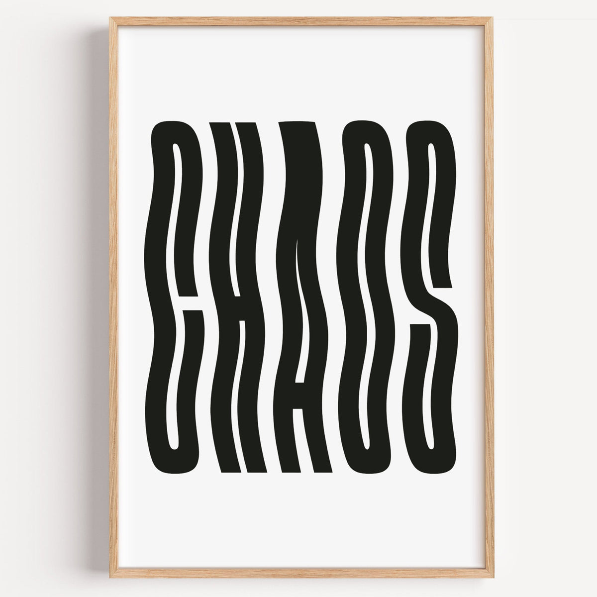 Wavy black CHAOS lettering on white print in a light oak frame on a plain white wall