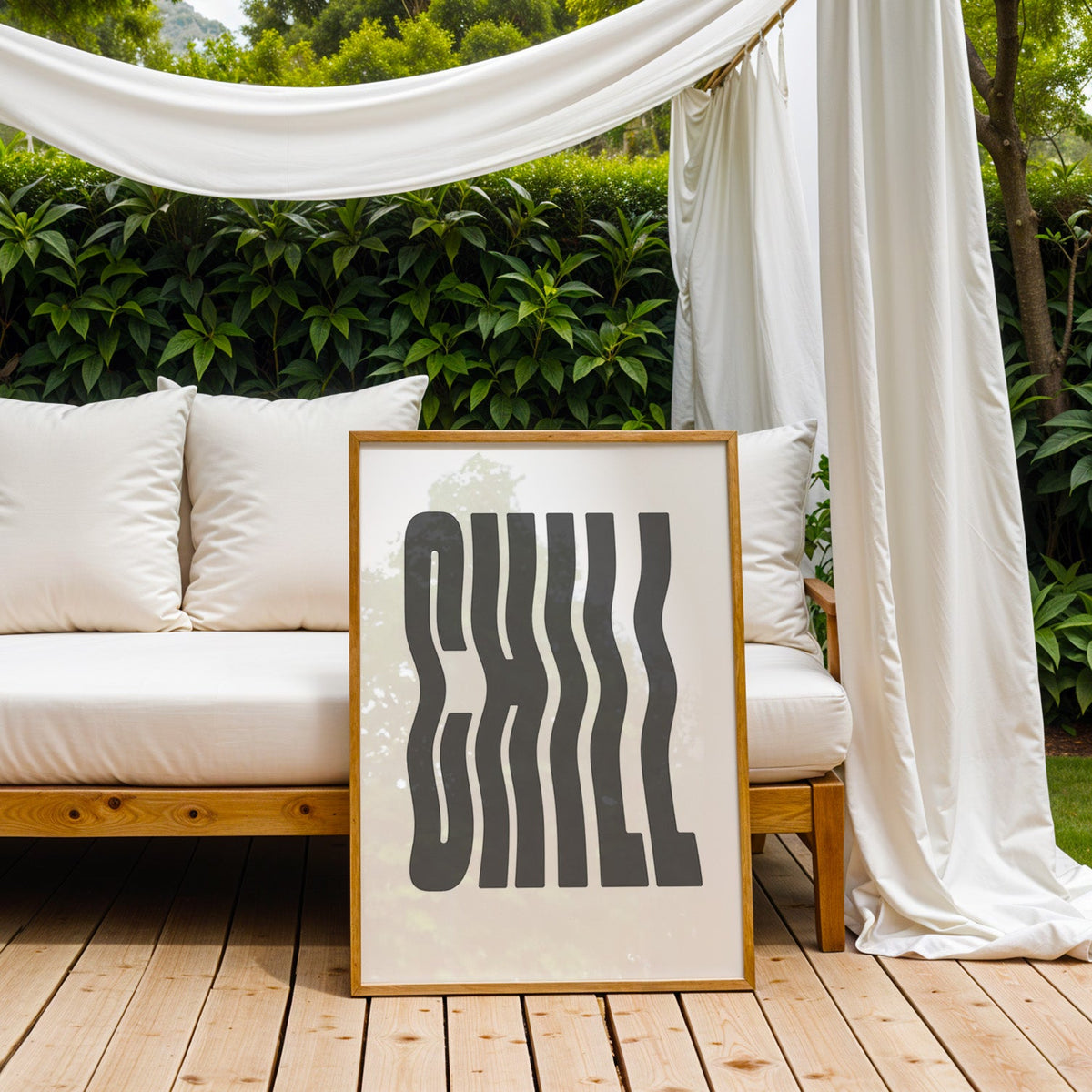Wavy CHILL lettering on white print in an oak frame on an outdoor daybed under white drapes