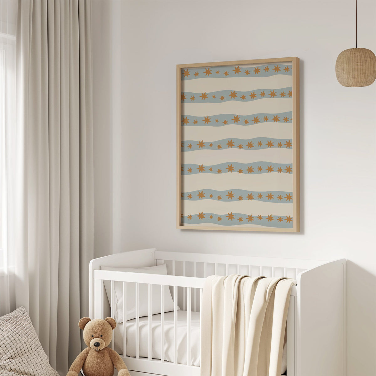 Wavy stripe stars pattern nursery print in an oak frame above a white crib with a teddy bear