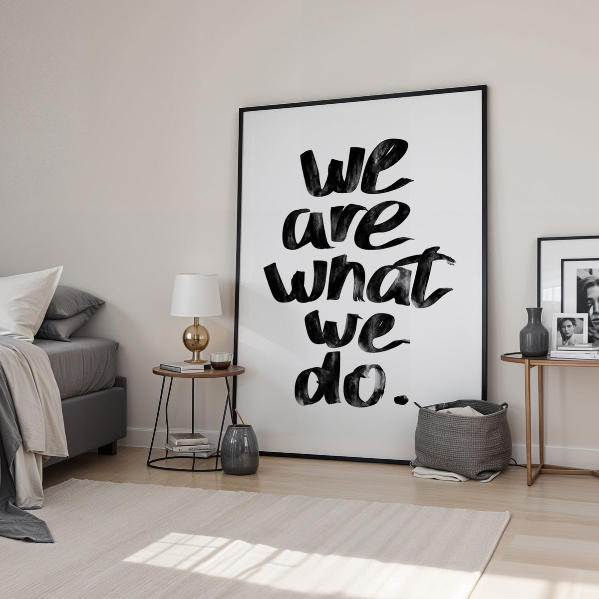 We are what we do brush lettering quote print in a black frame leaning in a bedroom beside a gold lamp