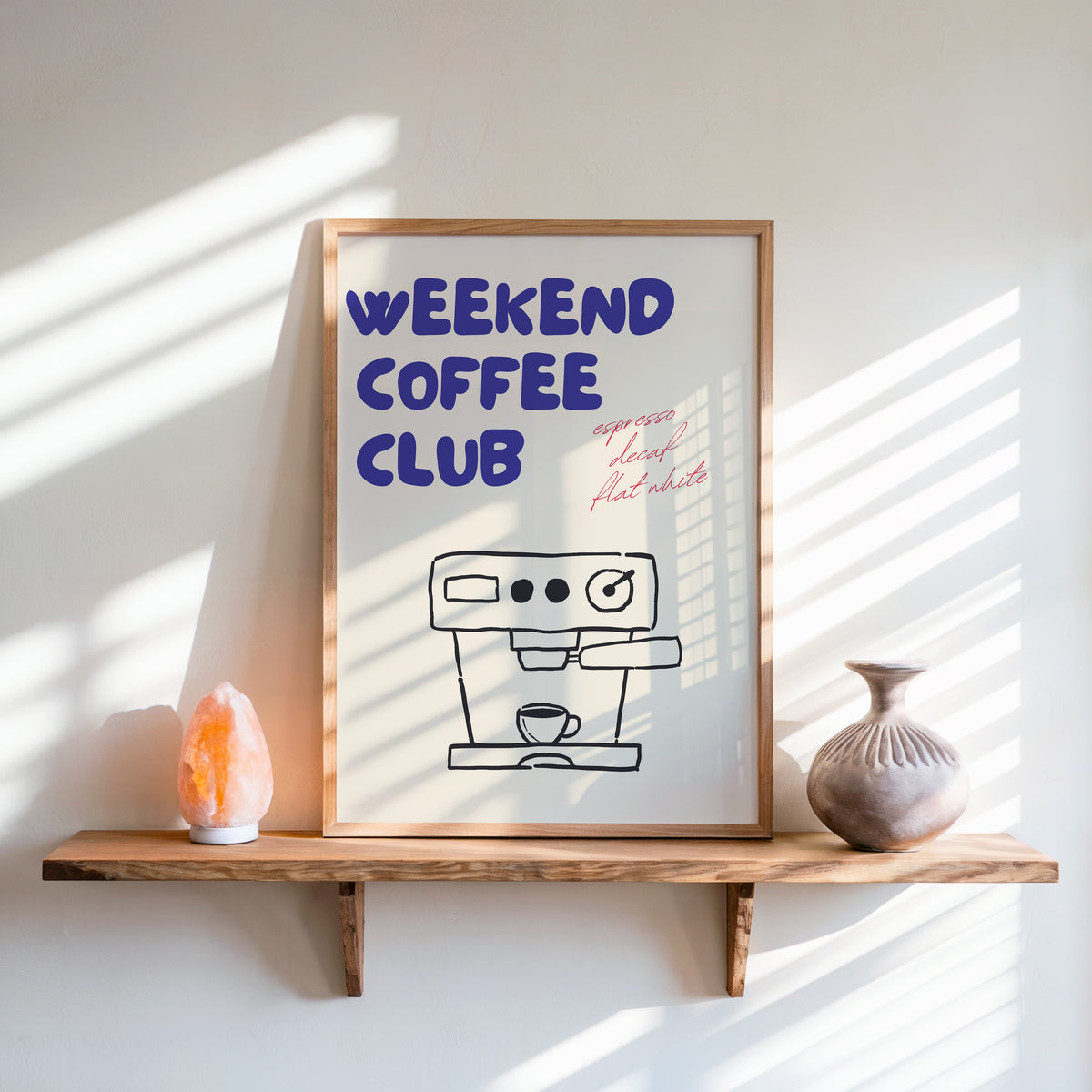 Weekend Coffee Club print in an oak frame on a live-edge shelf beside a salt lamp