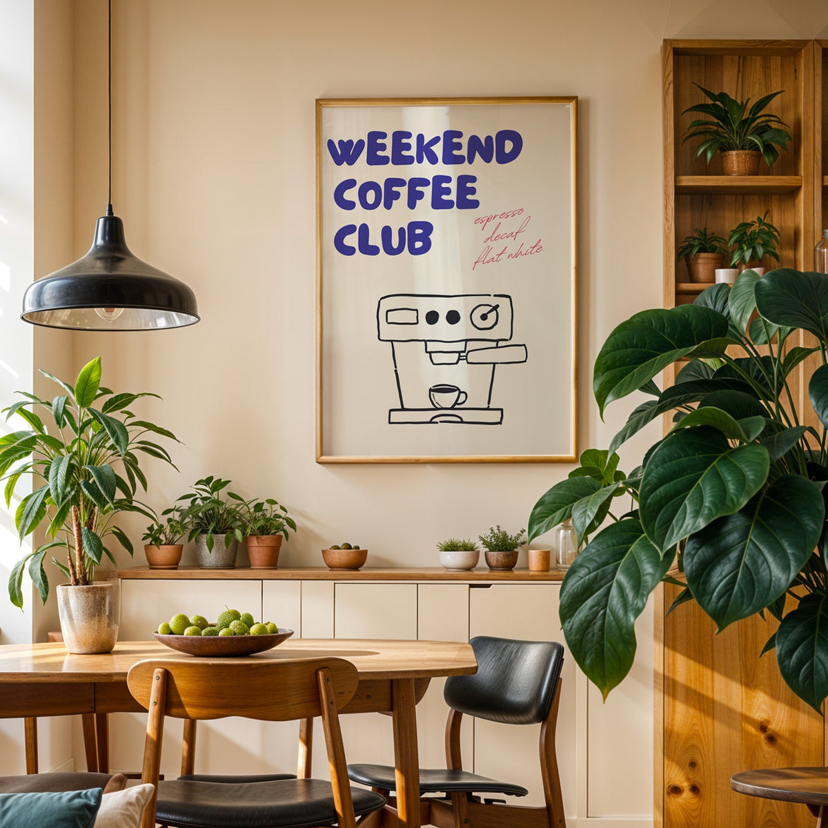 Weekend Coffee Club print in an oak frame in a dining room above a plant-lined sideboard