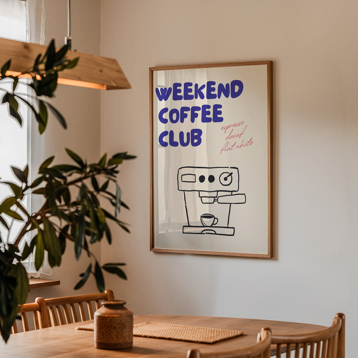Weekend Coffee Club print in a walnut frame above a dining table with olive branches