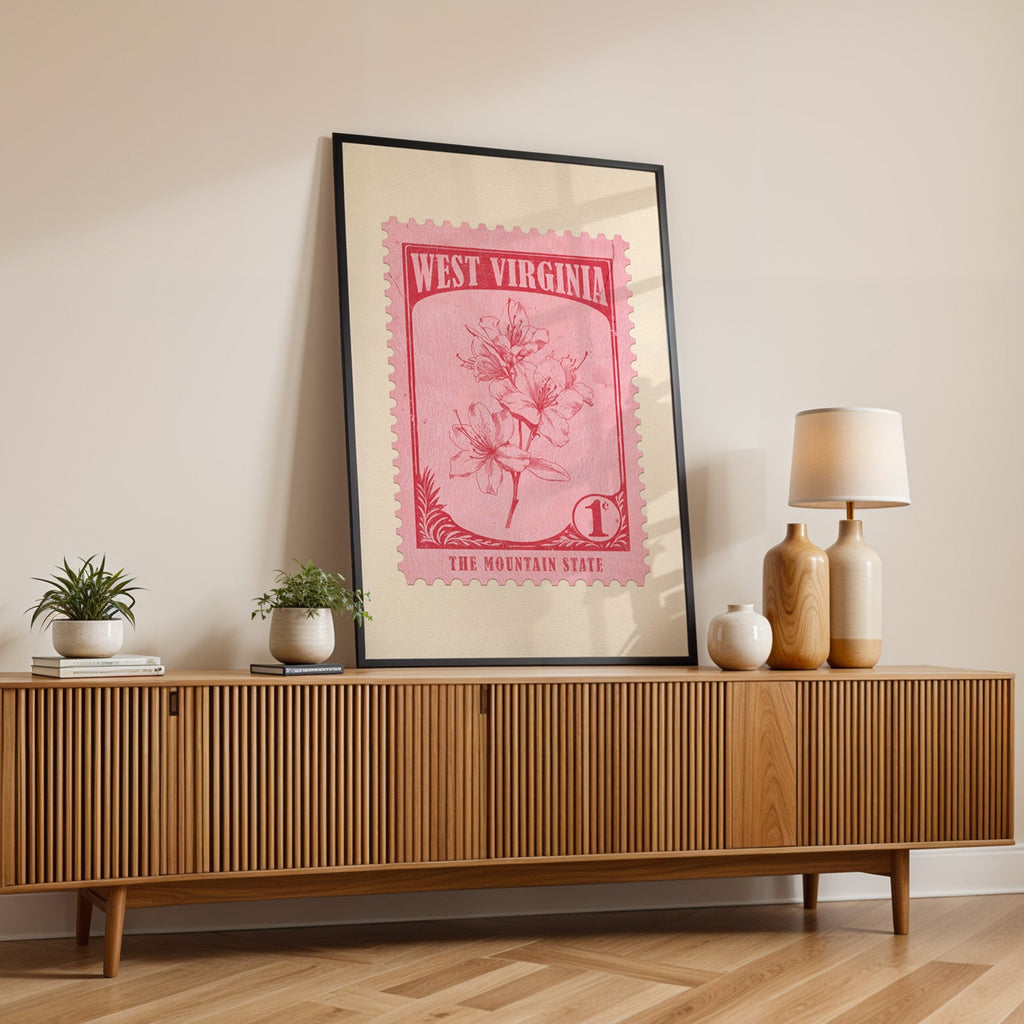 West Virginia state flower print in a black frame leaning on a fluted wood credenza with a lamp