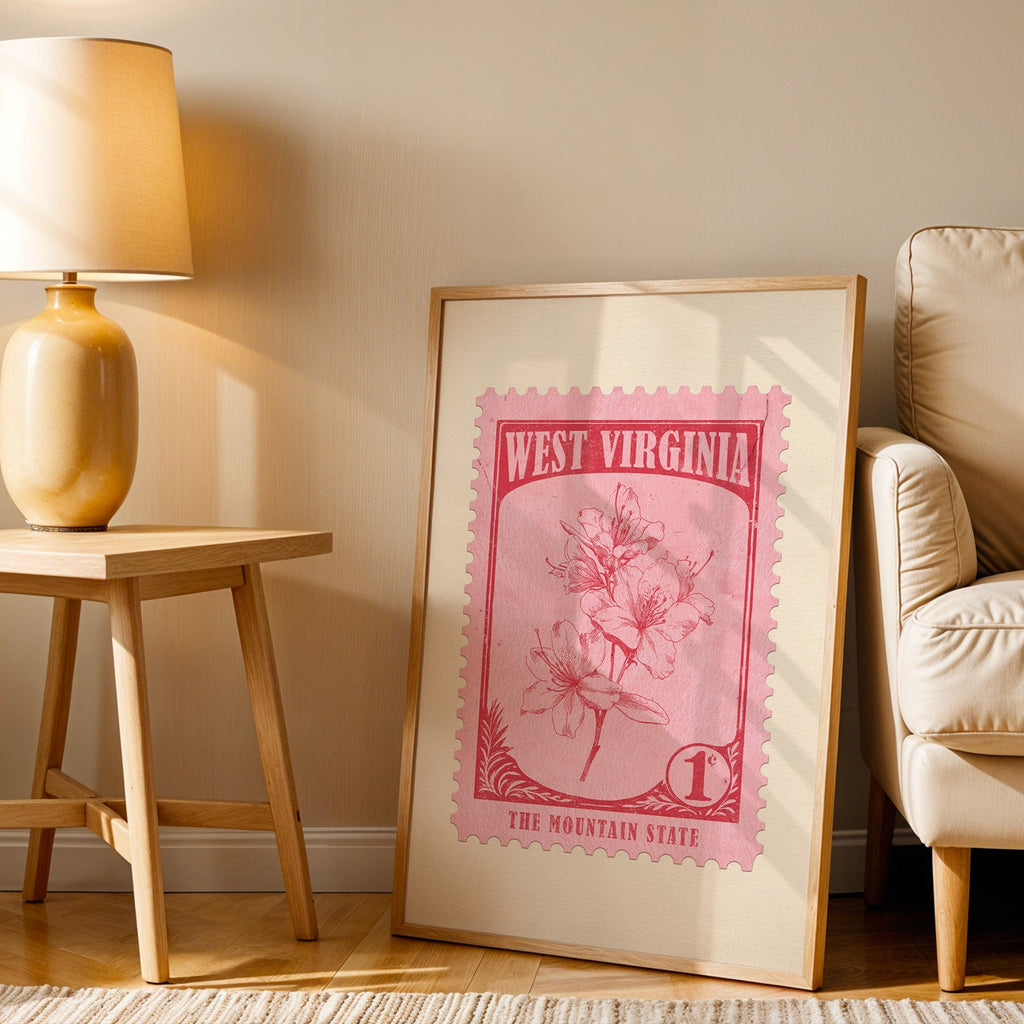 West Virginia stamp print in a wood frame resting on the floor by a beige armchair and yellow lamp