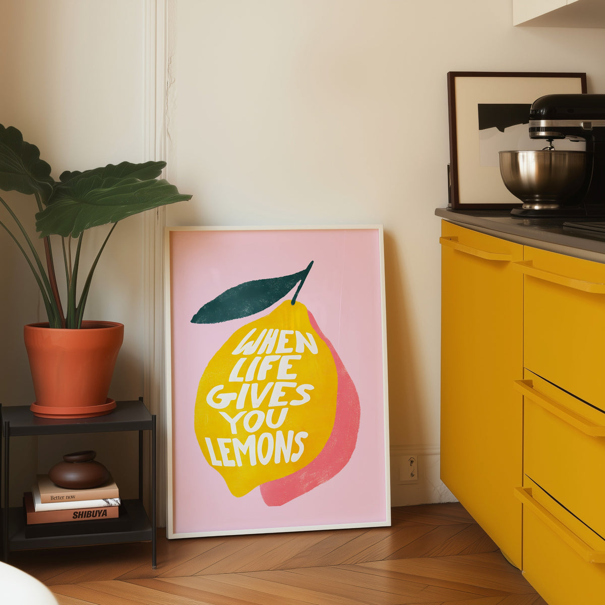 Lemon quote print in a white frame on parquet beside a bright yellow kitchen