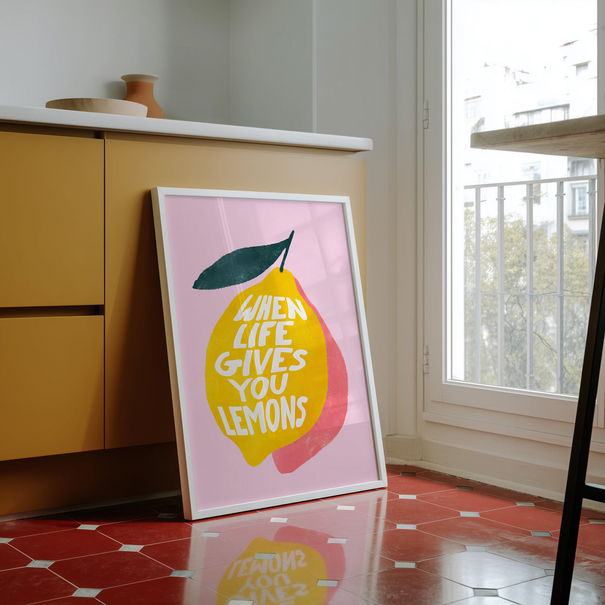 Lemon quote print in a white frame against yellow cabinets on a red tiled floor