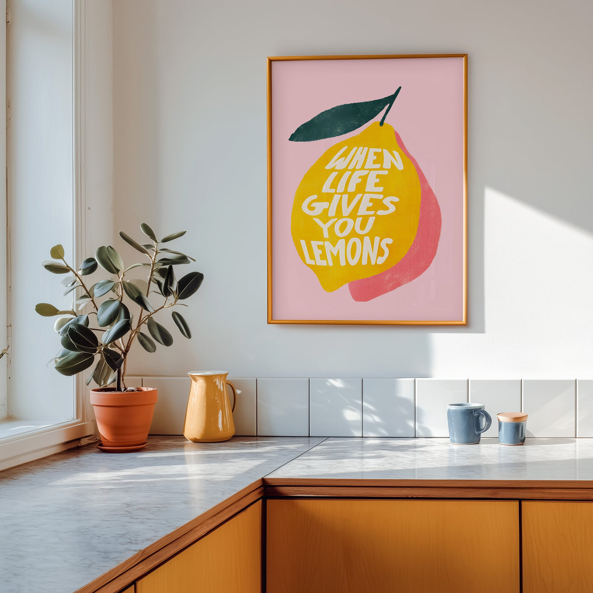 Lemon quote print in a gold frame above a marble counter with a yellow ceramic jug