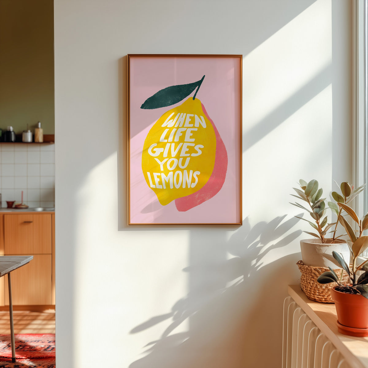 Lemon quote print in a gold frame in sunlight with plants and a kitchen beyond