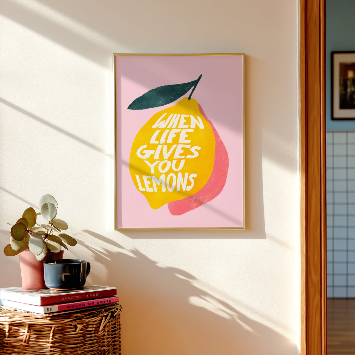 Lemon quote print in a gold frame above a basket of books and a pilea plant