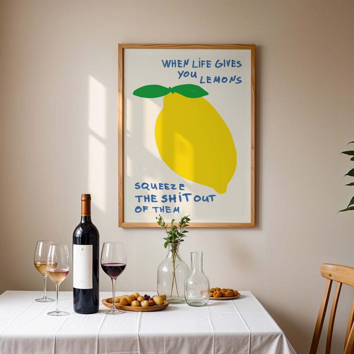 When life gives you lemons print in an oak frame above a table laid with red wine