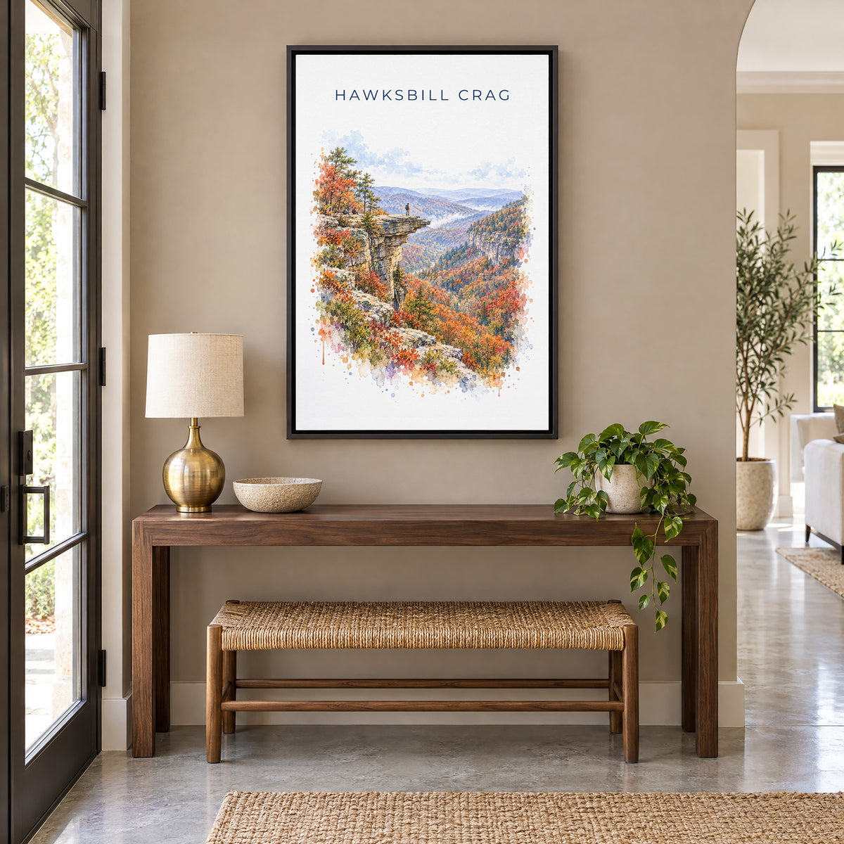 Hawksbill Crag watercolor print as a black floater canvas above a walnut console and woven bench in an entryway