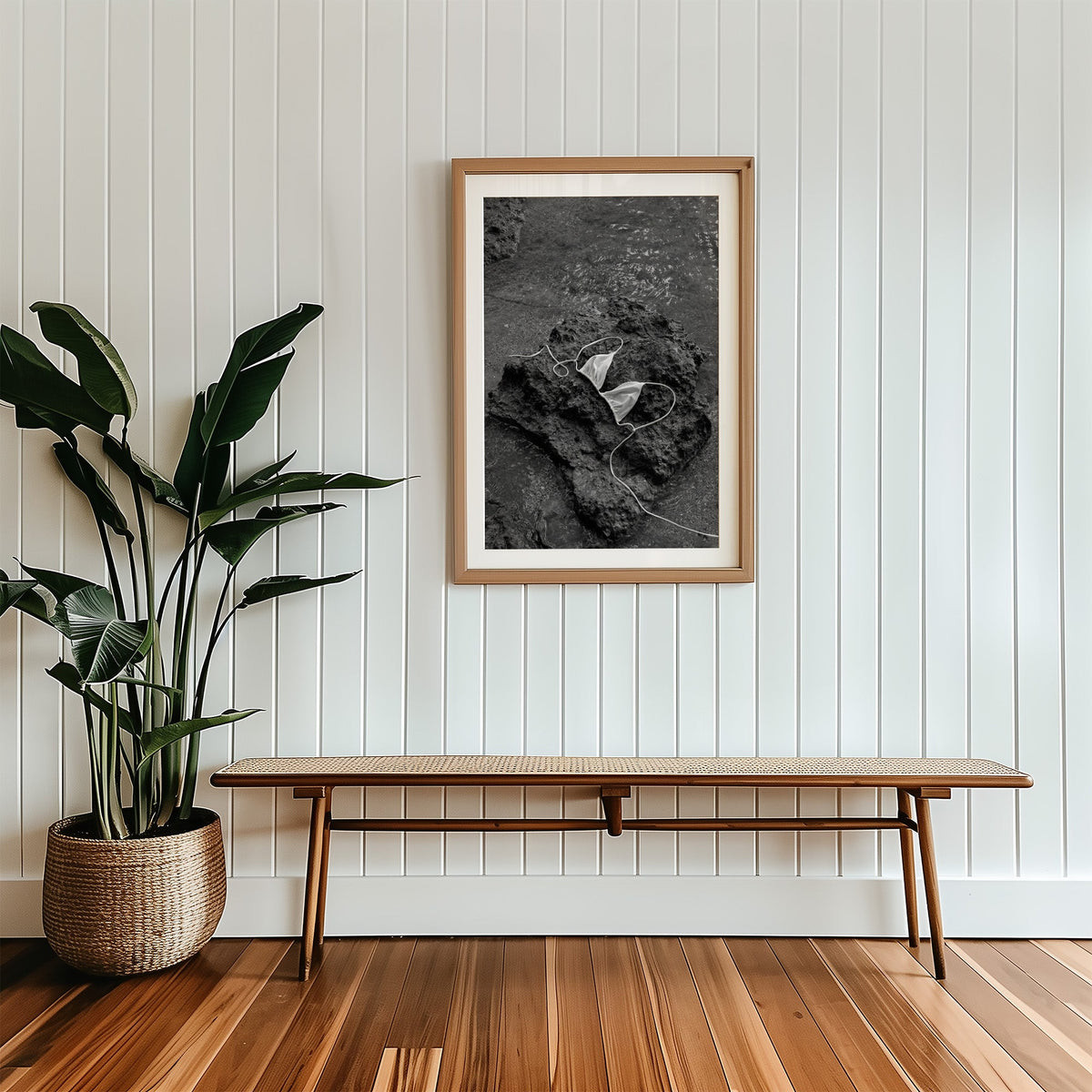 White bikini top on dark volcanic rock print in a wood frame with a white mat above a cane bench