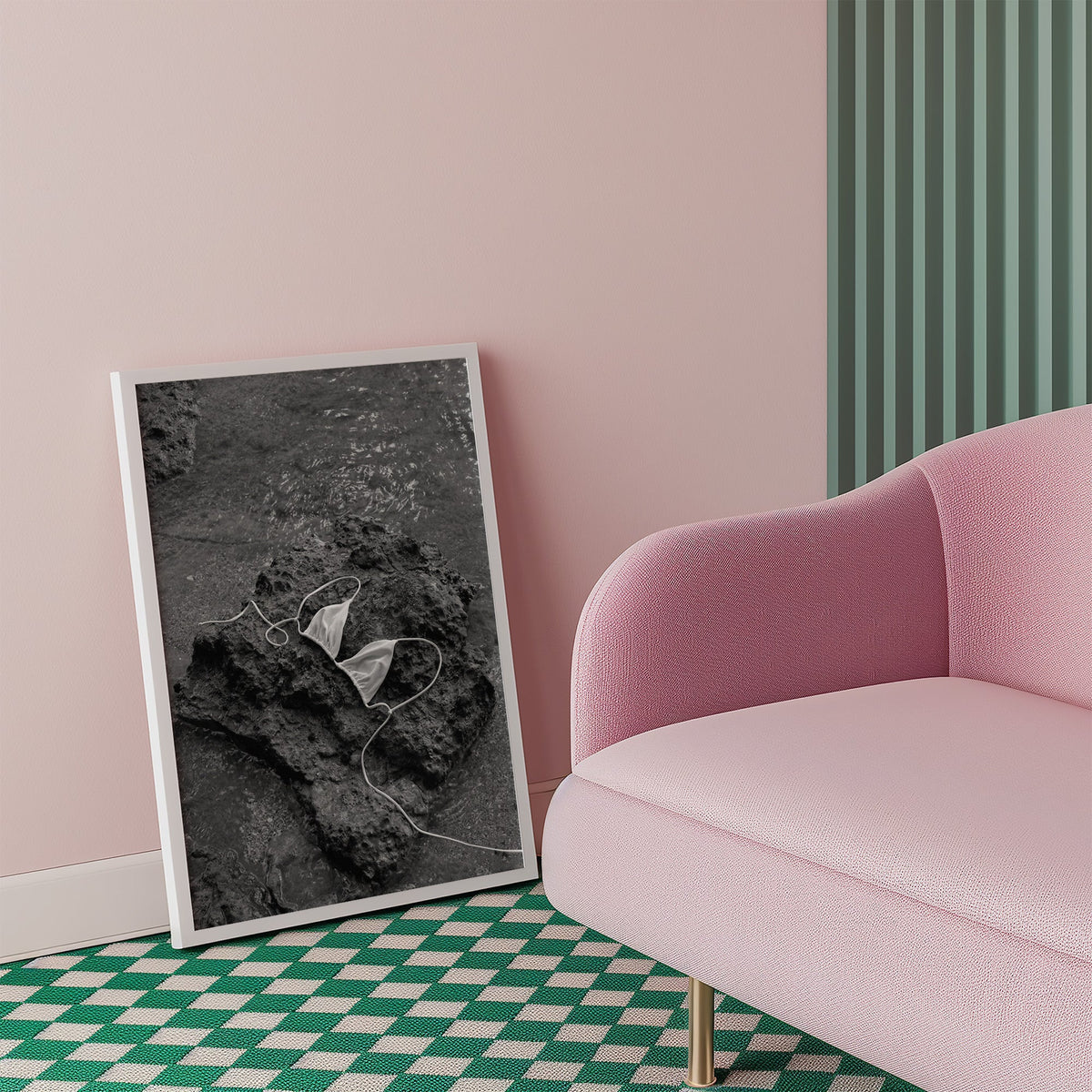 White bikini top on dark volcanic rock print in a white frame beside a pink armchair on a checkered floor