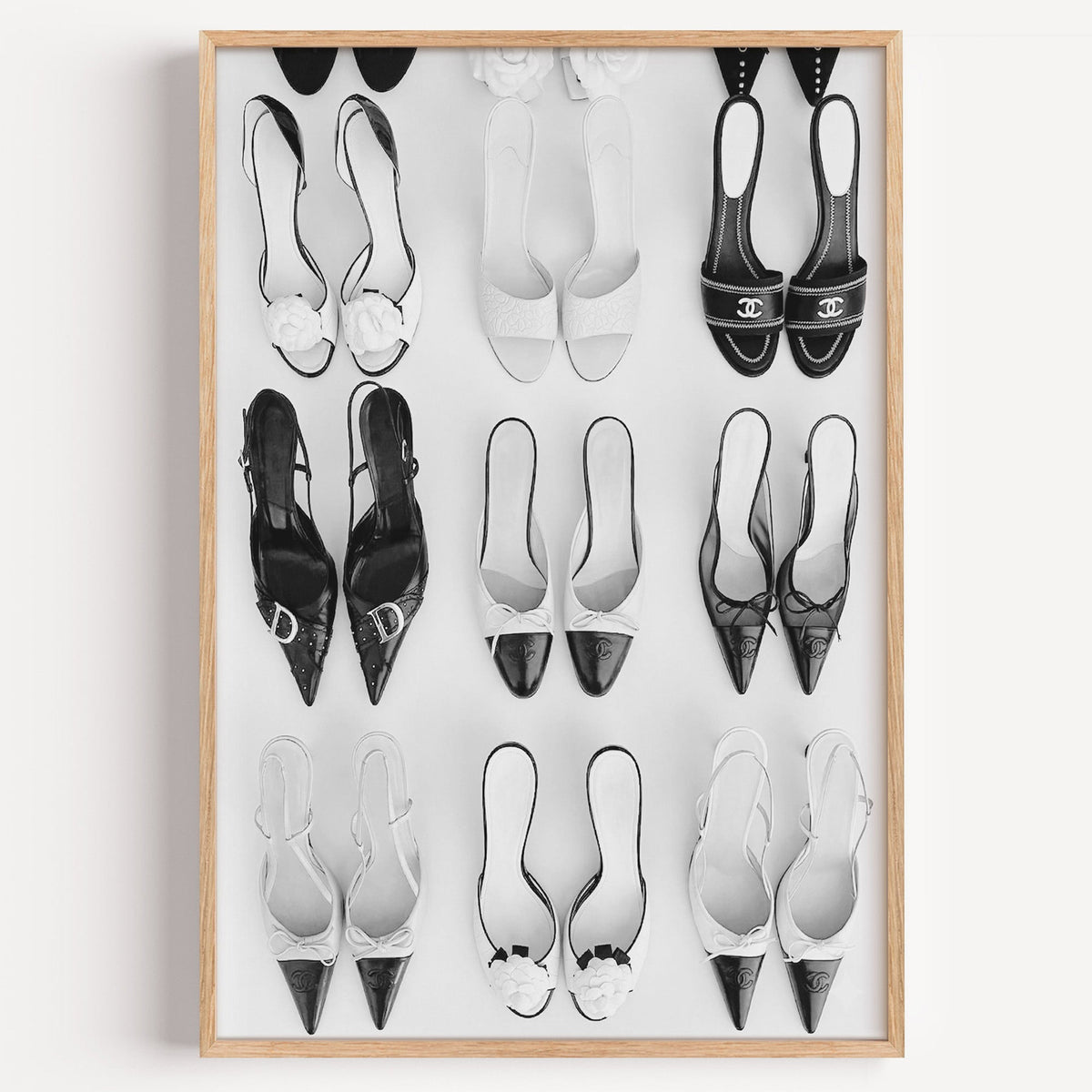 Nine pairs of mules and slingbacks in a grid print in a light oak frame on a plain white wall