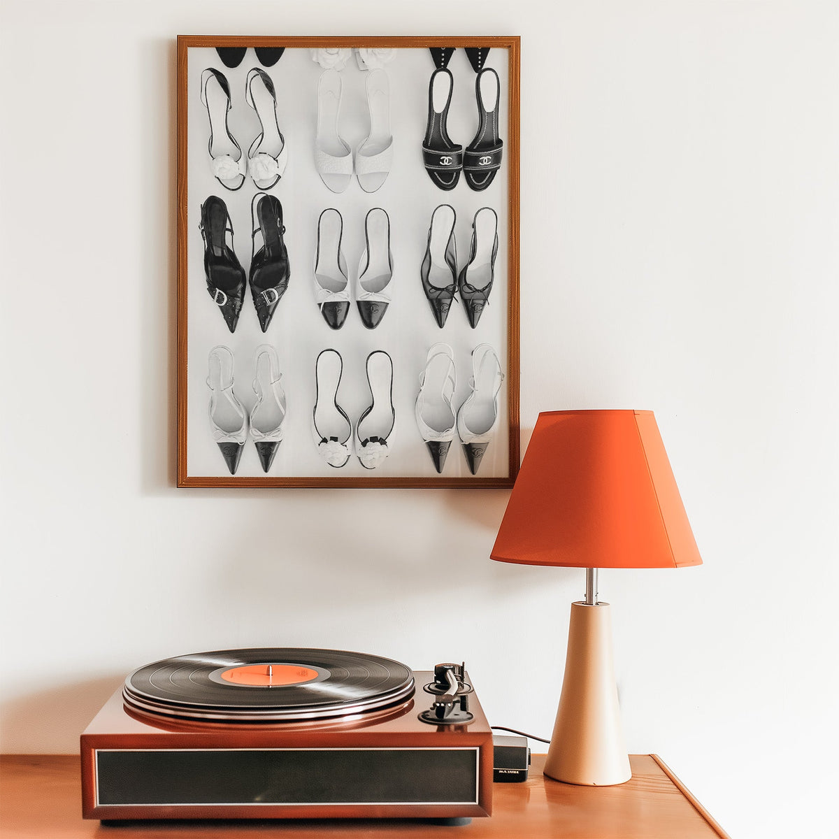 Nine pairs of mules and slingbacks in a grid print in a walnut frame above a record player and orange lamp