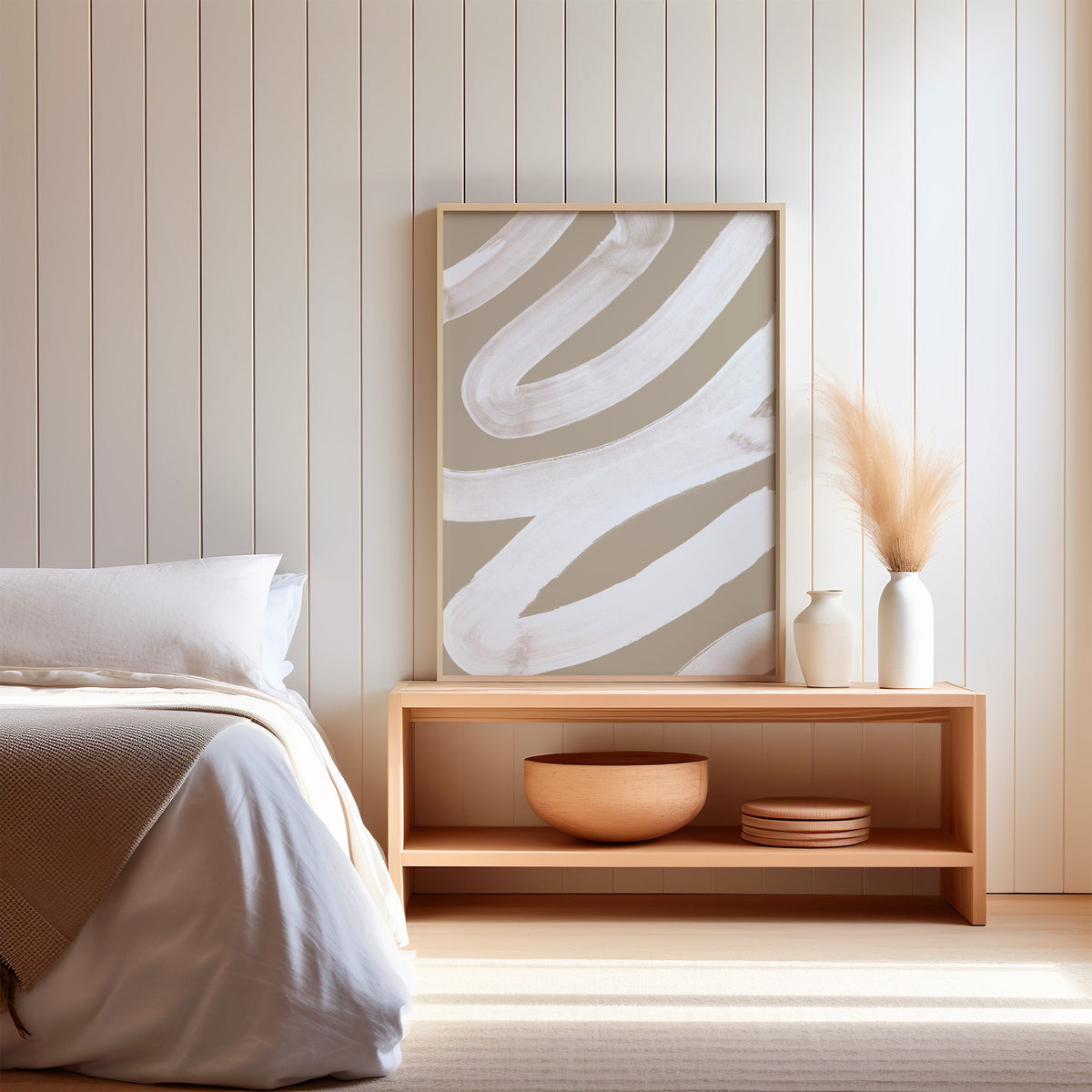 White brush zigzag on sand beige print in a light oak frame on a wood bench by a bed with pampas grass