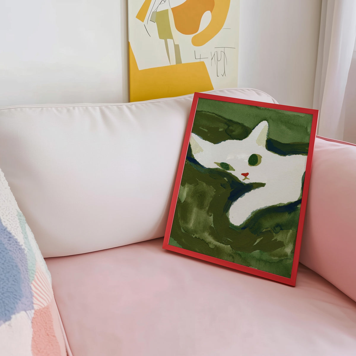 Modern white cat print shown in a red frame leaning on a blush pink sofa