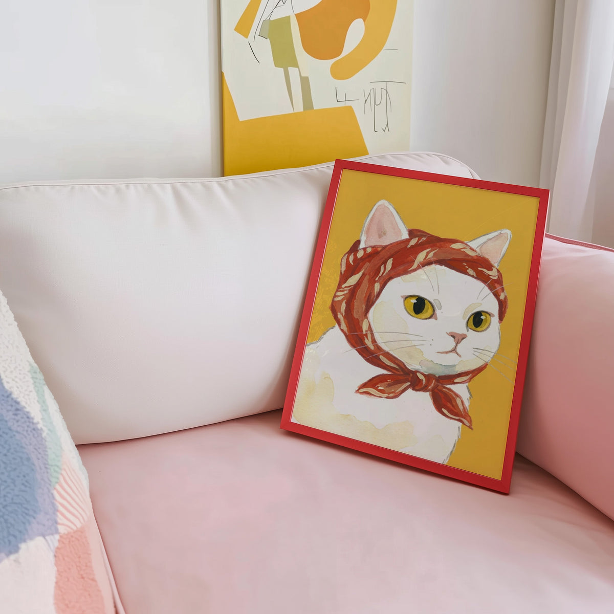 Watercolor white cat print shown in a red frame leaning on a blush pink sofa